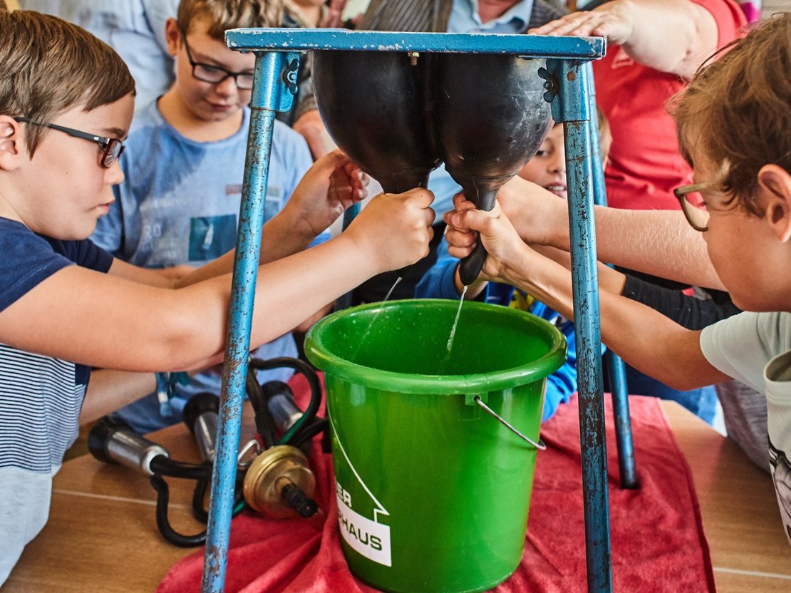 Kinder beim Melken eines Gummieuters