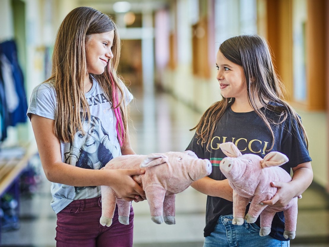 Kinder mit Spielschweinen in der Hand